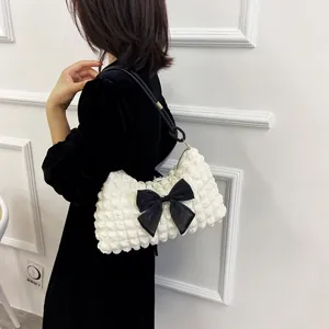 Detail of white puff texture shoulder bag featuring a large black decorative bow