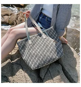 Détail du sac cabas en toile avec motif monogramme et pendentif en métal doré en forme de R