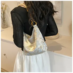 Detail of floral jacquard hobo bag with vintage resin chain strap on shoulder