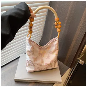 Detail of pink fabric bag with butterfly patterns and round wooden bead handle