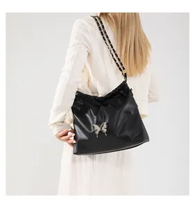 Detail of black cloud bag with silver butterfly buckle and chain strap on model