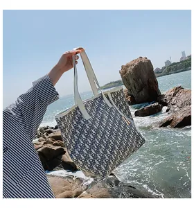 Détail du sac cabas en toile avec motif jacquard et breloque dorée R face à la mer