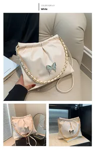 Detail of white pleated bucket bag featuring silver butterfly clasp and gold chain strap