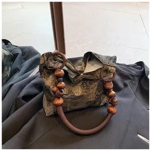 Detail of vintage fabric handbag with golden leaf embroidery and polished wooden bead handle