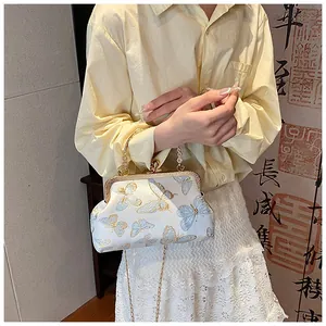 Detail of white satin shell bag with butterfly embroidery and pearl metal handle