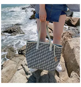 Détail du sac cabas en toile avec motif jacquard et breloque R dorée au bord de mer