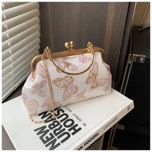 Detail of vintage shell bag with butterfly embroidery and golden metal clasp handle