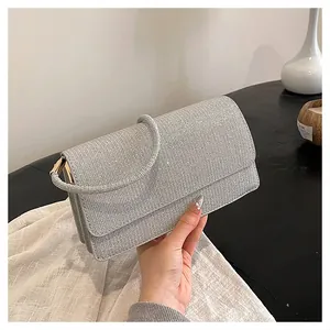 Detail of silver sequined evening bag with thick handle and metallic textured finish