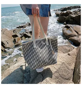 Gros plan du sac cabas en toile avec imprimé monogramme R et pendentif en métal doré