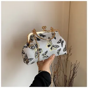 Detail of vintage gray shell bag with gold butterfly embroidery and metal ring handle