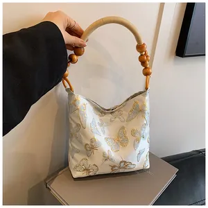 Detail of butterfly embroidered fabric tote with decorative wooden bead handle and rope