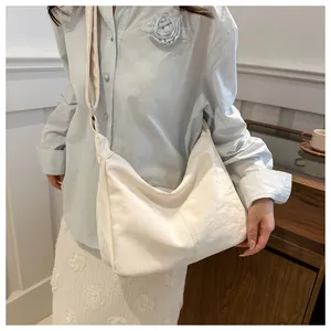 White pleated tote bag in textured faux leather worn by model in a bright setting