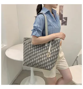 Détail du sac cabas en toile monogrammée avec anses en cuir et pendentif doré R