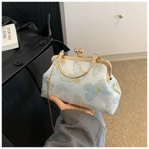 Detail of light blue cheongsam style handbag with butterfly jacquard and gold handle