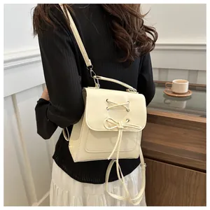 Detailansicht eines cremeweißen Mini-Rucksacks mit Schleife und Band an einem Model
