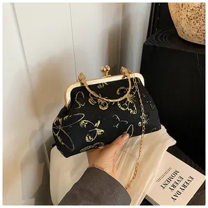 Detail of vintage black clutch bag with golden butterfly embroidery and metal clasp
