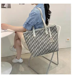 Détail du sac cabas en toile avec motifs de lettres et pendentif en métal doré R