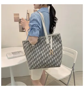 Détail du sac cabas en toile monogrammé avec pendentif R sur une chemise à rayures