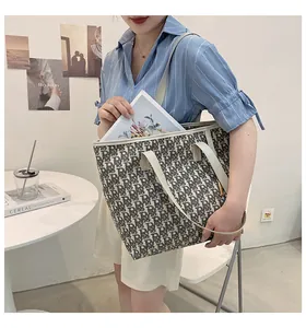 Détail du grand sac cabas en toile avec imprimé monogramme et longues anses en cuir