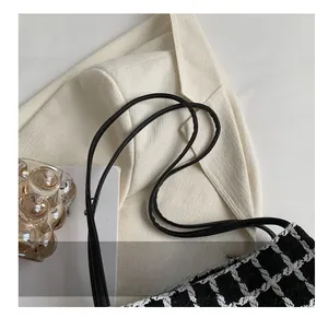 Close-up of black and white plaid tweed shoulder bag with comfortable strap detail