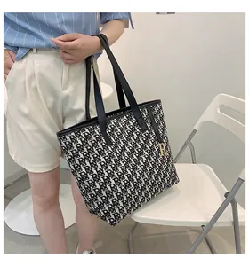 Vue détaillée d'un sac cabas à monogramme noir et blanc avec breloque dorée en R