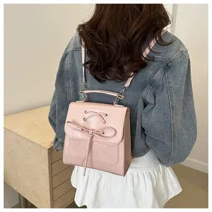 Detailansicht eines rosa Mini-Rucksacks mit Schleifen-Dekor, Metallgriff und Trägern