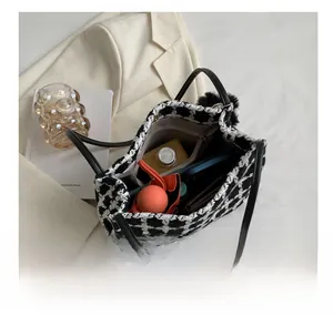 Internal view of houndstooth tote bag with zipper pocket, black handle and plush ball