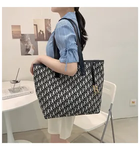 Détail du sac cabas en toile avec motif jacquard de lettres et breloque dorée