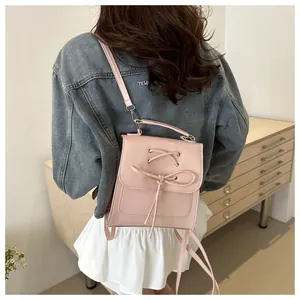 Detail eines rosa PU-Leder-Minirucksacks mit Schleife und silbernen Ösen am Modell