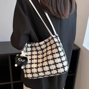 Detail of checkered tweed tote bag with plush charm and slim white shoulder straps