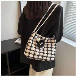 Chic black and white tweed checkerboard tote bag with a cute fuzzy monster bag charm