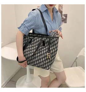 Détail du cabas en toile avec motif monogramme R et pendentif en métal doré chic