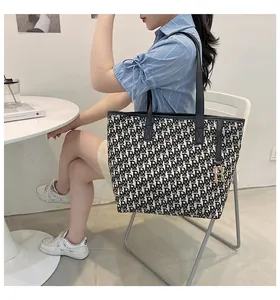 Détail du sac cabas en toile avec motif monogramme noir et blanc et pendentif R doré