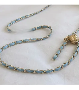 Gros plan sur la bandoulière en cuir bleu clair tissé avec boucle boule dorée