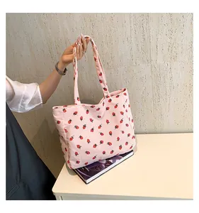 Détail du sac cabas en velours côtelé rose avec broderie fraise et large bandoulière