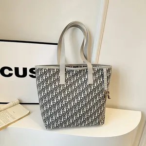 Sac fourre-tout en toile à monogramme avec anses en cuir et pendentif doré dans un décor épuré