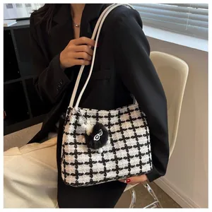 Classic black and white checkered tote bag with plush charm on a model in a black blazer