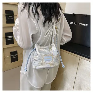 Détail d'un sac seau en jacquard bleu clair avec cordon et bandoulière chaîne