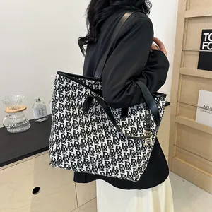 Grand sac cabas en toile avec sangles en cuir noir et imprimé monogramme sur l'épaule