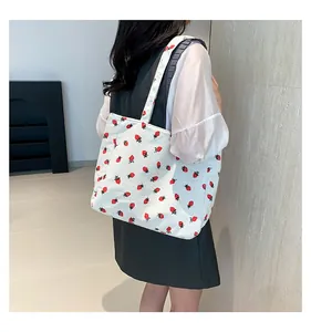 Texture détaillée du sac fourre-tout en velours côtelé blanc avec imprimé fraise rouge