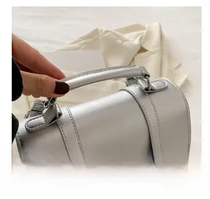 Detail of silver metallic handbag featuring a butterfly buckle and sturdy top handle
