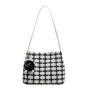 Classic black and white tweed bucket bag with white shoulder strap and plush charm