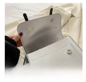 Close-up of dual magnetic snap closures on a white leather bag with neat stitching
