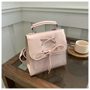 Detail der rosa PU-Ledertasche mit Schleife und Schnürung auf einem Holztisch
