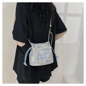 Détail du sac seau bleu clair avec texture de peinture dorée et bandoulière chaîne