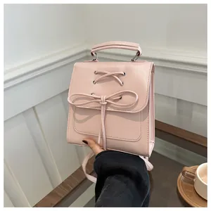 Detail eines hellrosa Mini-Rucksacks mit dekorativem Schnürbogen und glattem PU-Leder