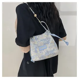 Détail du sac seau en jacquard bleu avec chaîne dorée et étiquette en cuir fashion