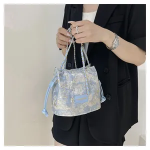Détail du sac seau en jacquard bleu clair avec chaîne dorée et fermeture à cordon