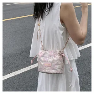 Détail du sac seau en jacquard rose avec bandoulière chaîne et cordon de serrage