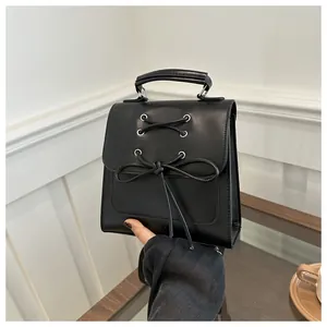 Nahaufnahme einer schwarzen Mini-Lederhandtasche mit Schleife und Schnürung aus Metallösen